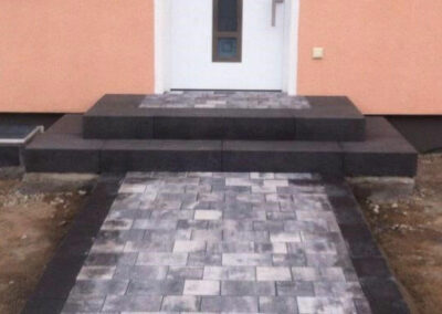 Eingang eines roten Hauses gepflastert mit grauen Steinen