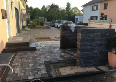 gepflasterter Eingangangsbereich eines Hauses mit Steinwand
