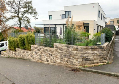 Mauer aus hellen Steinen als Begrenzung zum garten