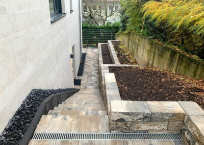 gepflasterter Eingangsbereich mit Treppe und Beeten in Terrassenform
