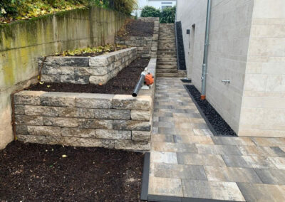 gepflasterter Eingangsbereich mit Treppe und Beeten in Terrassenform