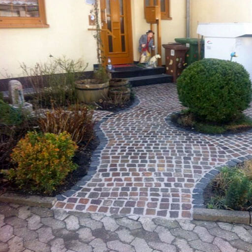 gepflasterter Eingangsbereich mit rötlichen Steinen die im Halbkreis angeordnet sind
