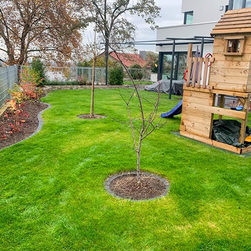 garten mit spielplatz neu angelegter Garten mit neu gepflanzten Bäumchen und Spielburg